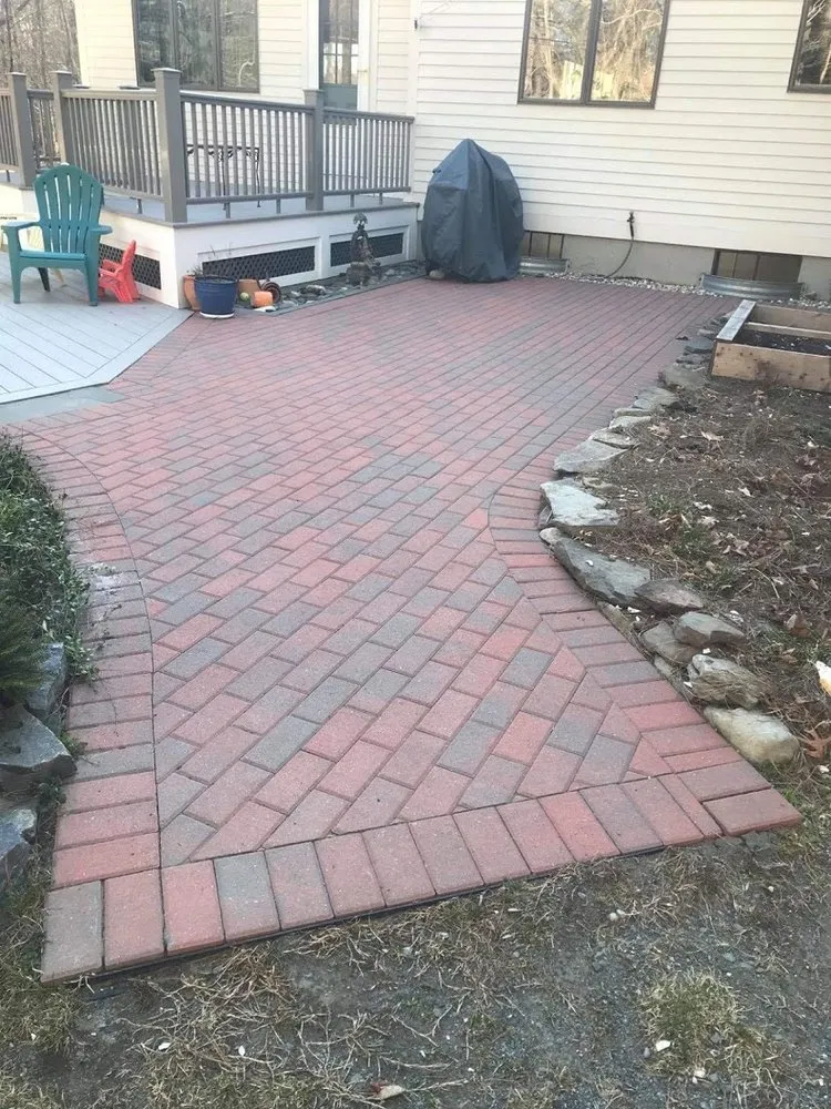 Red brick paver patio bordered by plantings