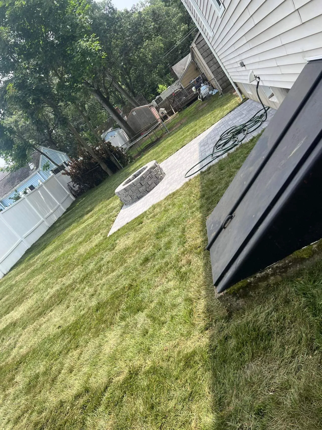 Backyard fire pit and freshly cut lawn beside a patio
