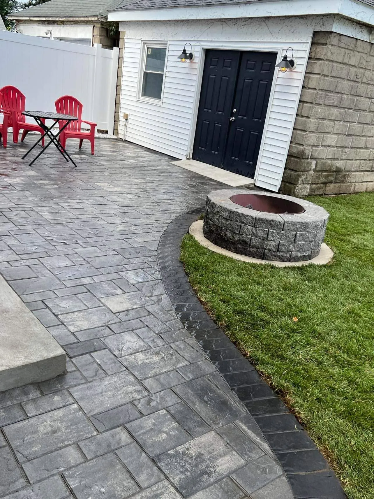 Stamped concrete patio with a round stone fire pit and bistro chairs